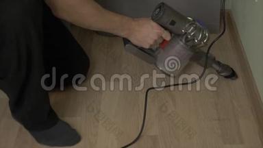 人在家用无线<strong>吸尘器</strong>清洁地板后修复.. 男人从家里的地板上拿出污垢。